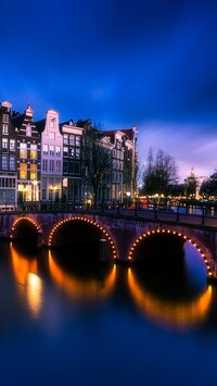 Oświetlony most nad rzeką w Amsterdamie