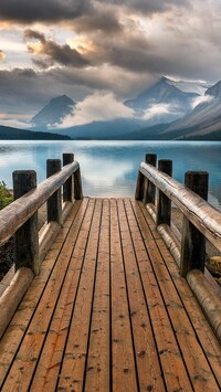 Pomost nad jeziorem Bow Lake i góry pod chmurami