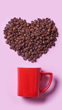 Serce z ziaren kawy nad kubkiem