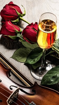 Skrzypce obok lampki wina i róż