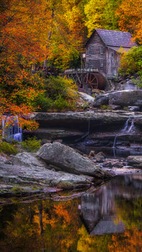 Stary młyn nad wodospadem wśród jesiennych drzew