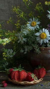 Truskawki obok kwiatów w wazonie