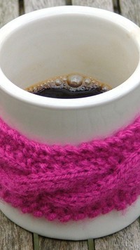 Wełniana opaska nałożona na kubek z kawą