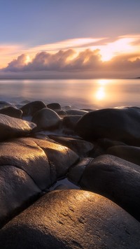 Wschód słońca nad morzem o kamienistym brzegu