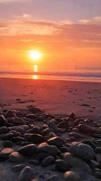 Zachód słońca nad kamienistą plażą