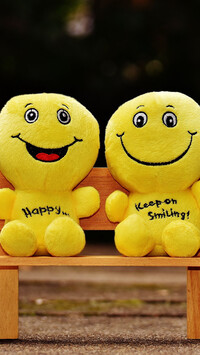Żółte uśmiechnięte maskotki na ławeczce
