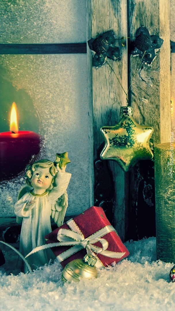 Aniołek i prezent świąteczny ze świecą w tle