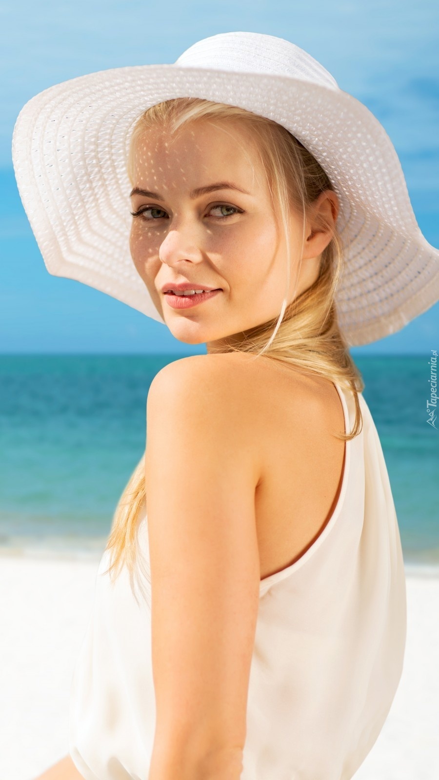 Blondynka w kapeluszu na plaży w tropikach