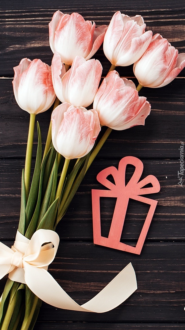 Bukiet bladoróżowych tulipanów z prezentem na ciemnych deskach