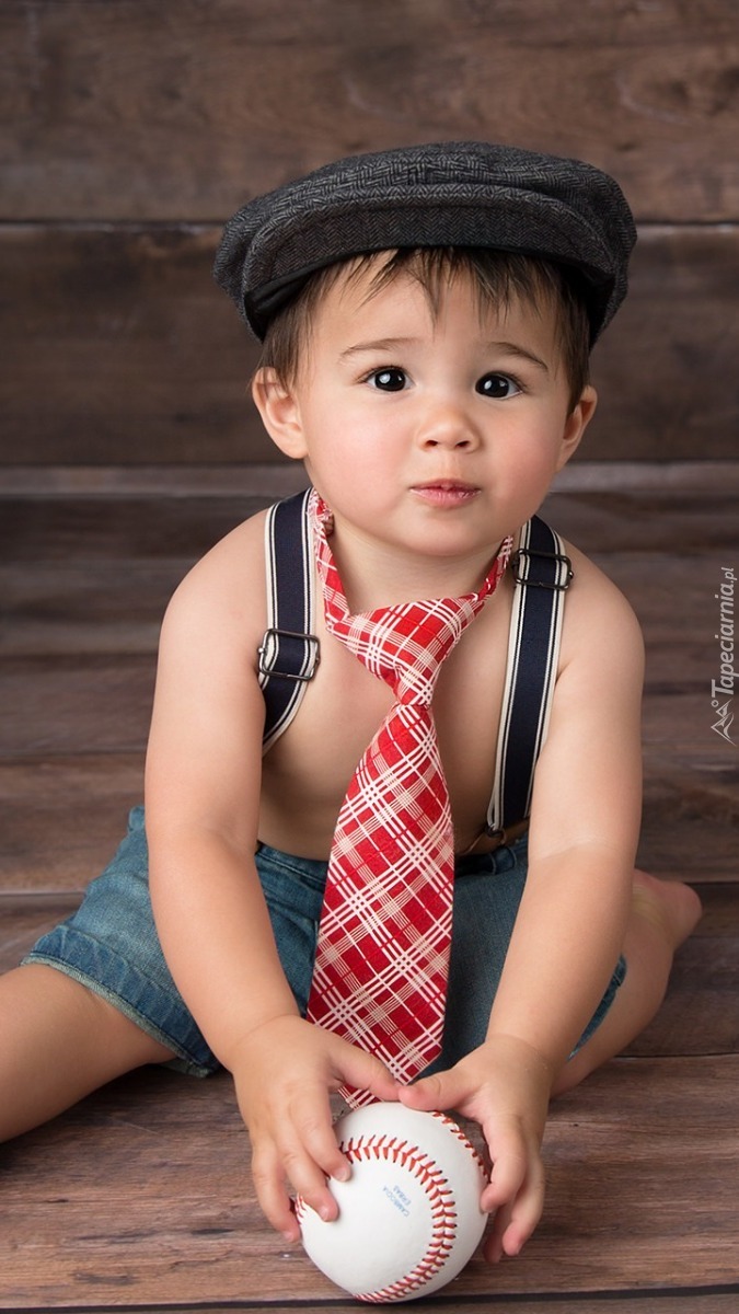 Chłopczyk w czapce i krawacie trzymający piłkę