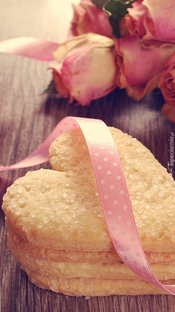 Ciasteczko w kształcie serca położone obok róż