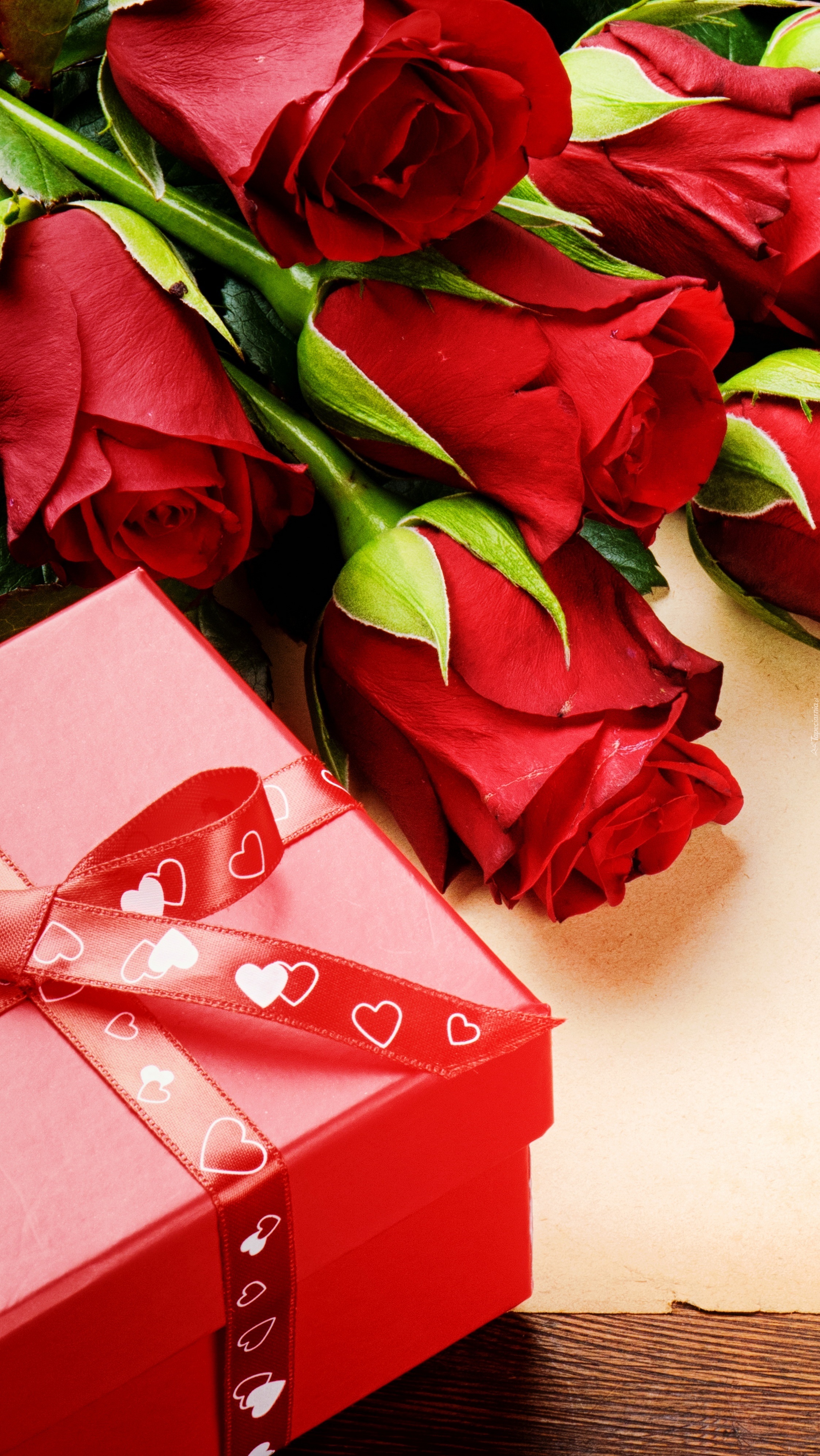 Czerwone róże obok pudełka przewiązanego wstążką
