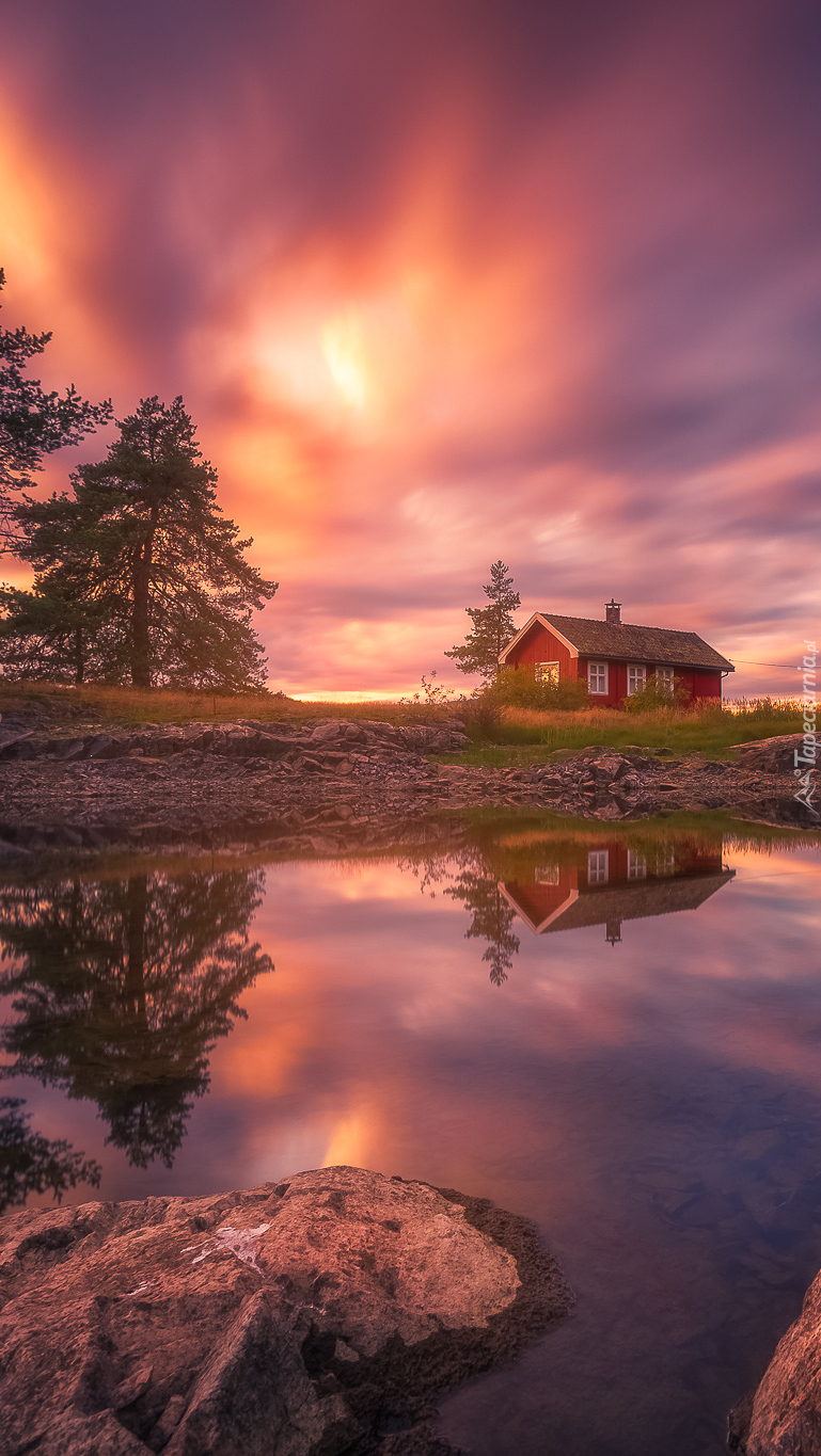 Czerwony domek nad norweskim jeziorem o zmierzchu