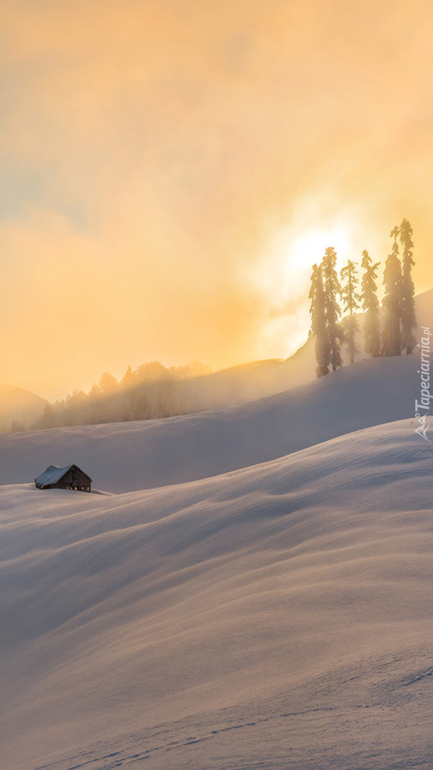 Dom na zaśnieżonym wzgórzu w blasku zachodzącego słońca