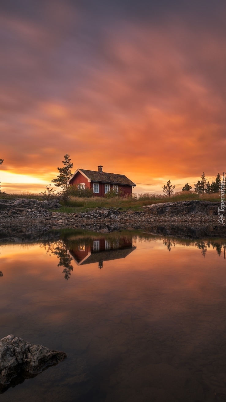 Dom nad jeziorem w Norwegii o zachodzie słońca