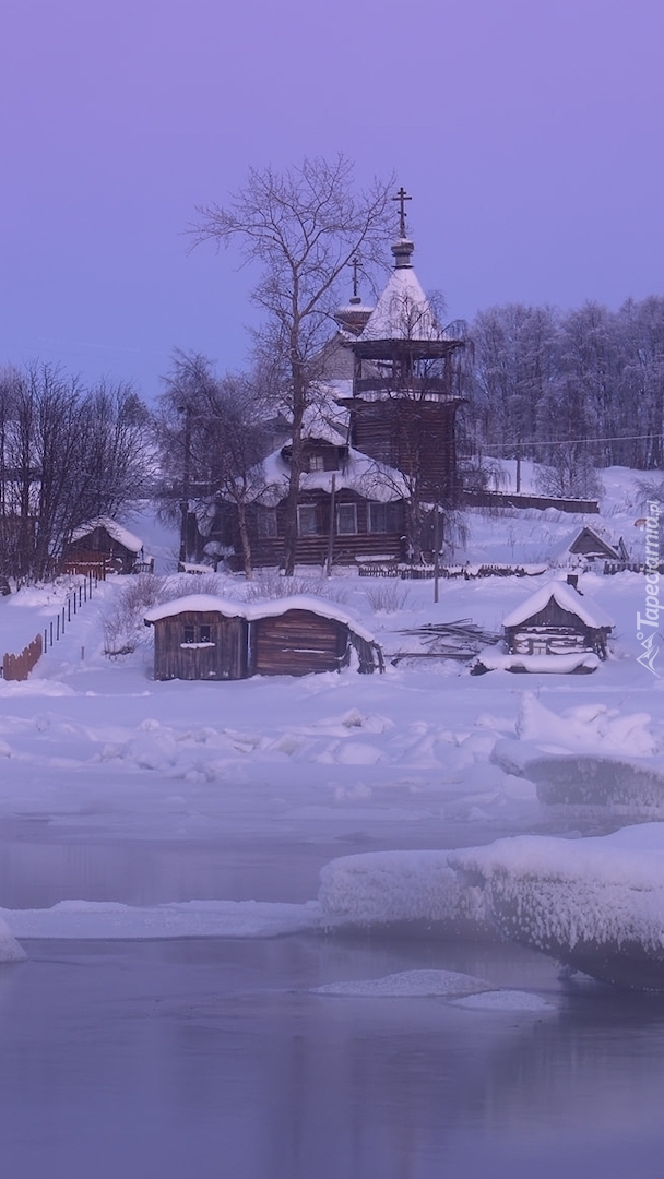 Domki i kościół nad oblodzoną rzeką