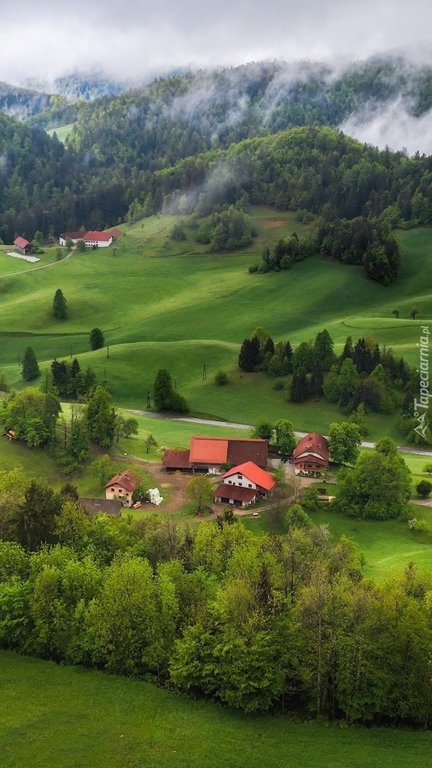 Domy w dolinie i zamglone góry