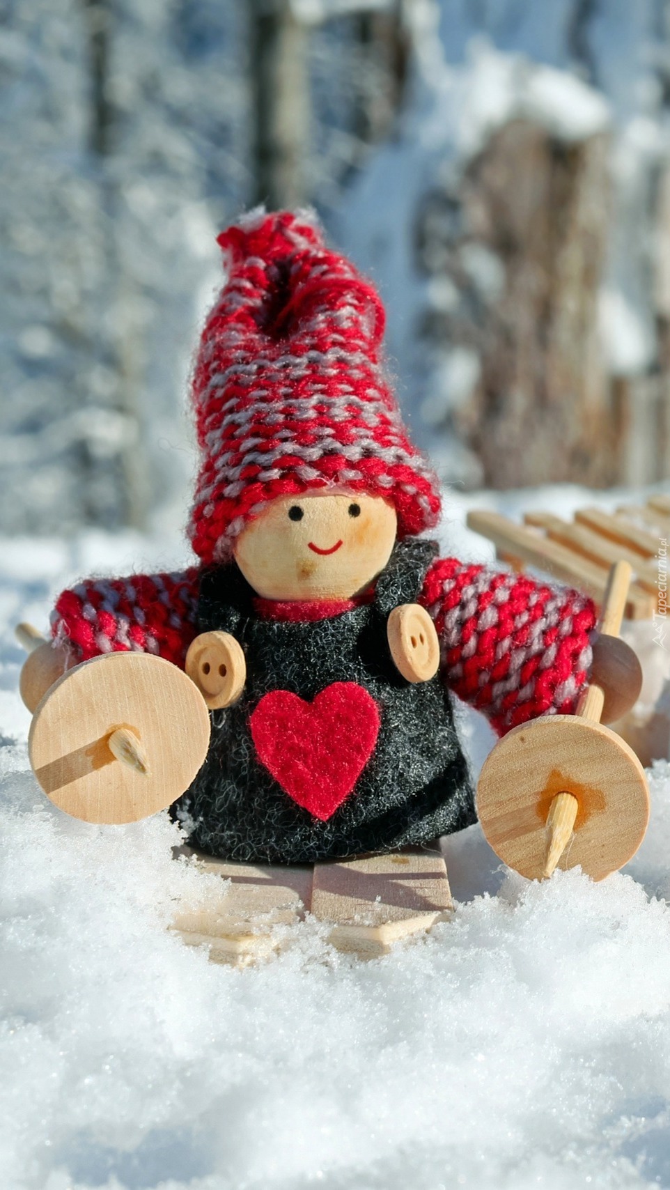 Drewniana laleczka z zabawkami i sankami na śniegu