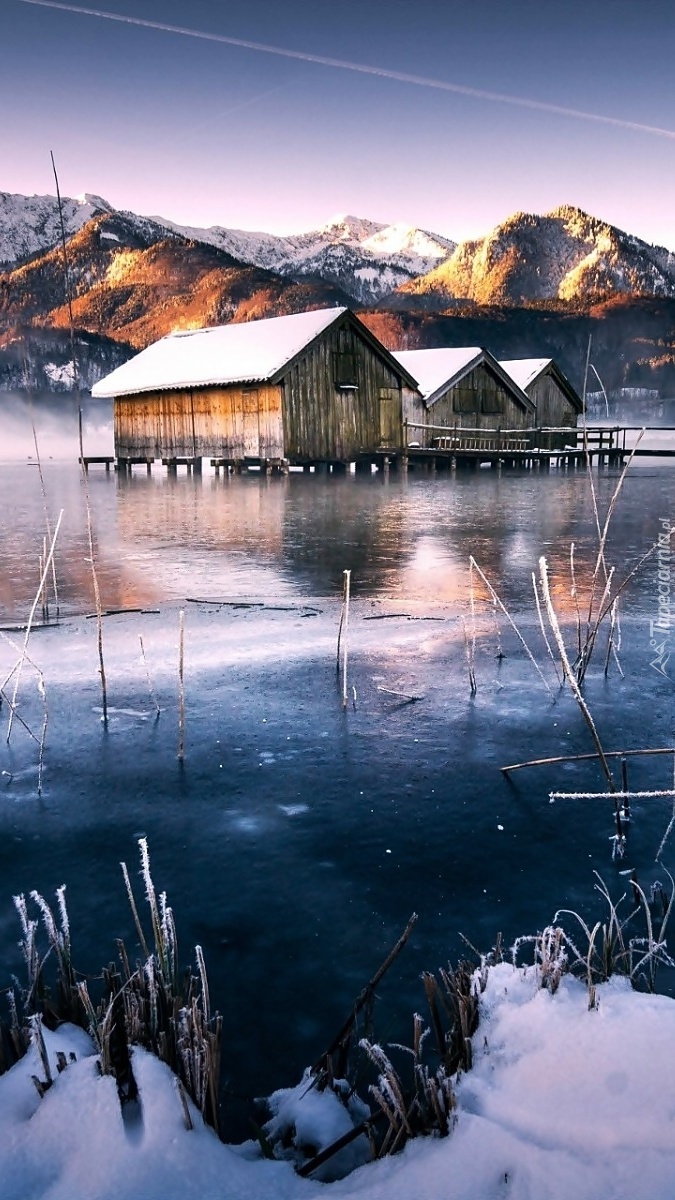 Drewniane domki na jeziorze w górach zimą