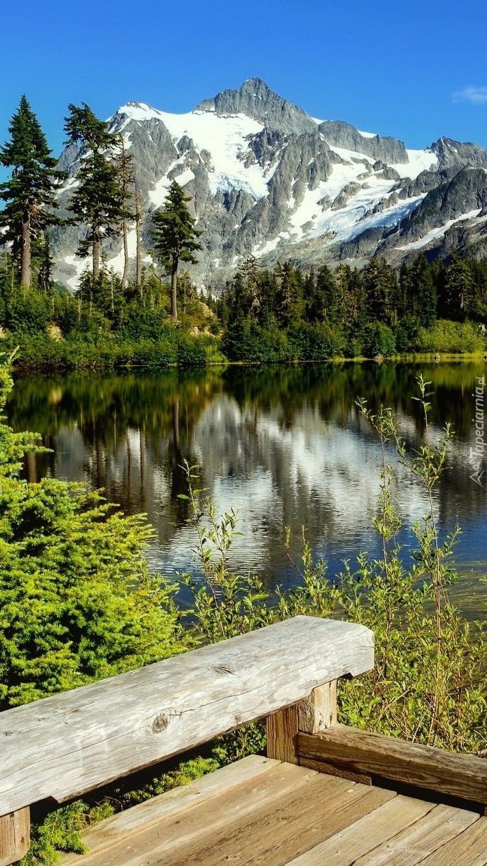 Drewniany pomost z którego widać góry i jezioro