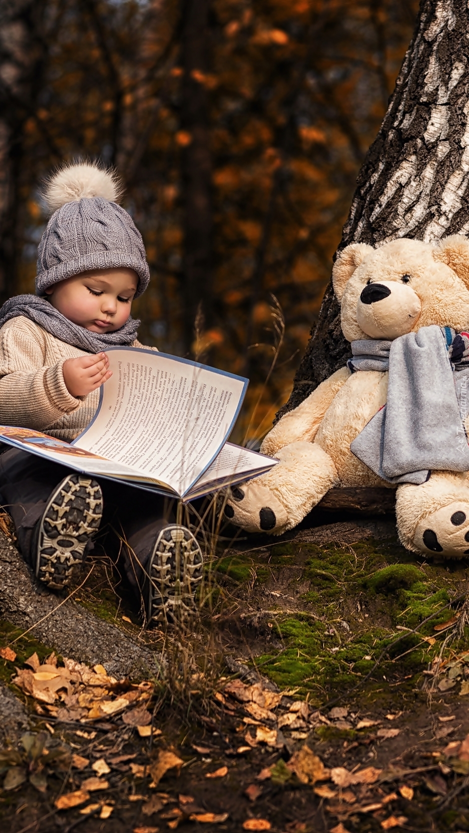 Dziecko z książką i pluszakiem pod drzewem