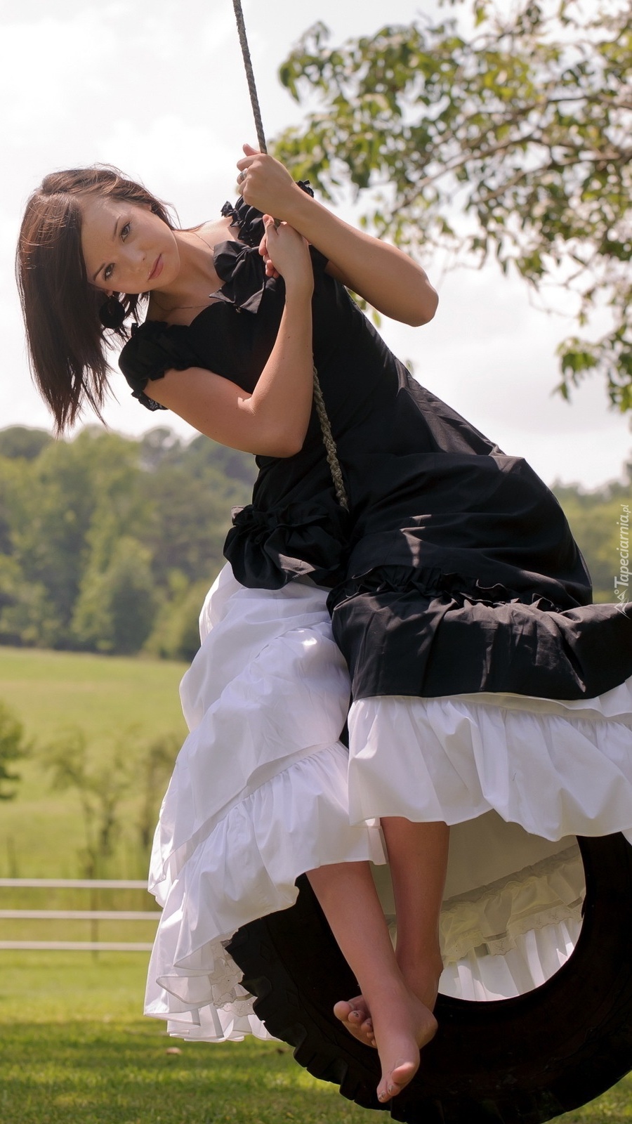 Dziewczyna w czarno-białej sukience na huśtawce