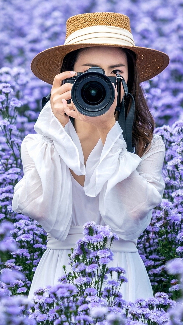 Dziewczyna z aparatem fotograficznym wśród kwiatów