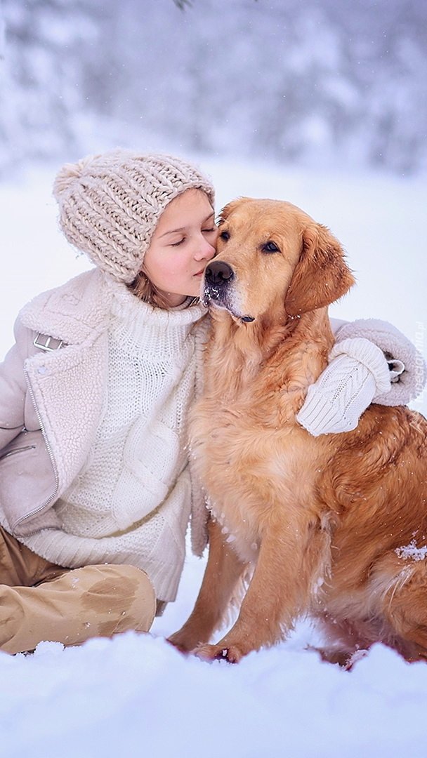 Dziewczynka i golden retriever na śniegu