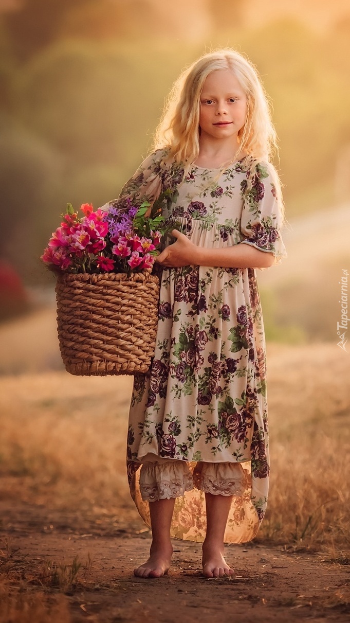 Dziewczynka na bosaka z koszem kwiatów na polnej ścieżce