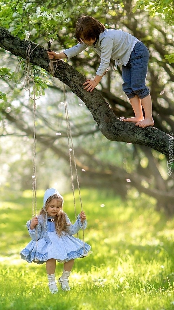 Dziewczynka na huśtawce i chłopczyk na drzewie
