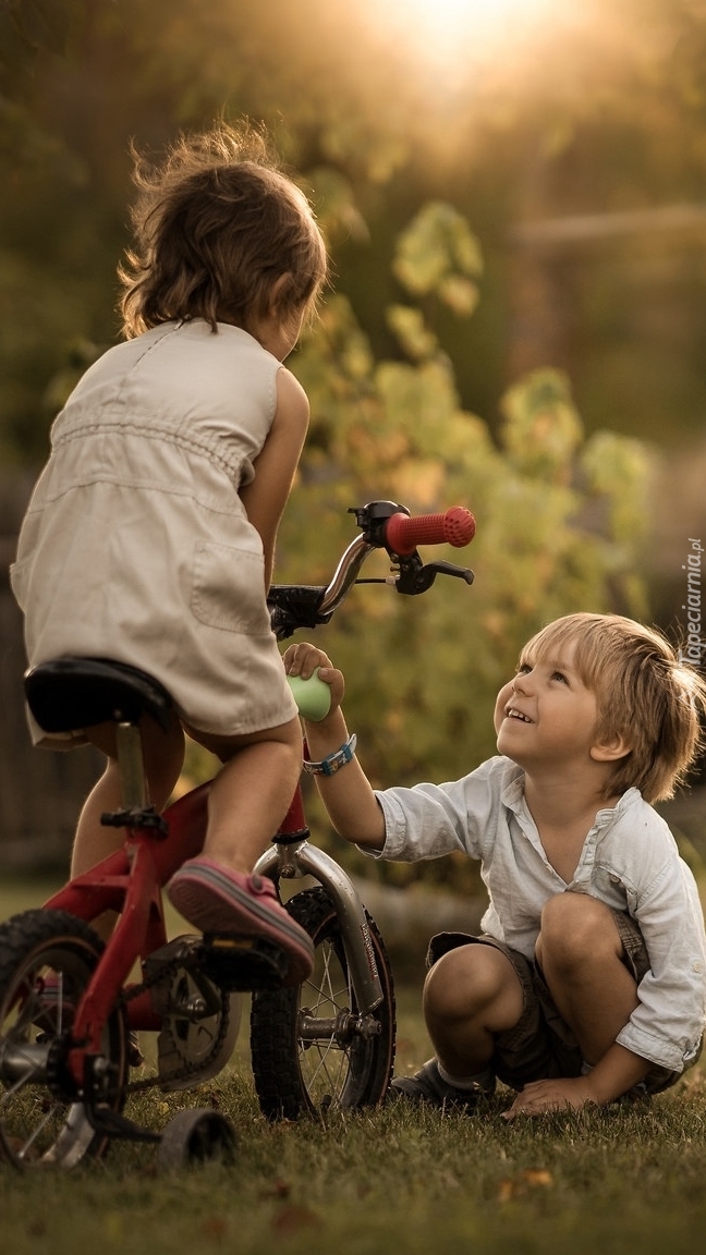 Dziewczynka na rowerze i kucający chłopiec