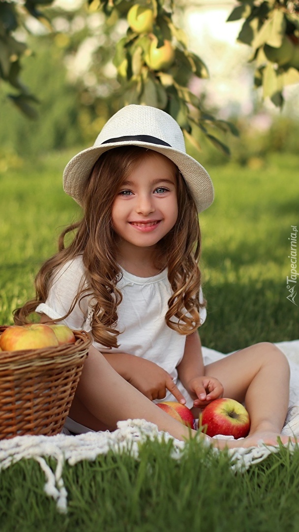 Dziewczynka obok kosza jabłek