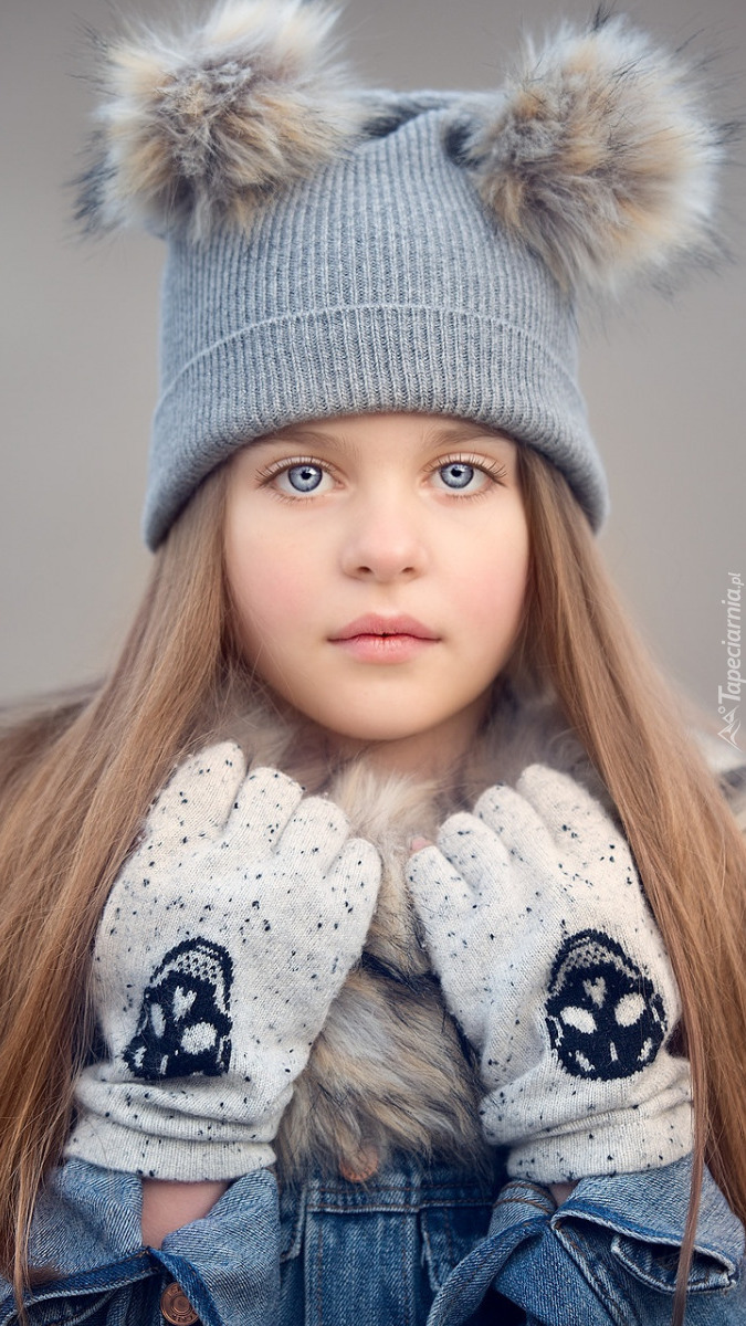 Dziewczynka w czapce z pomponami i rękawiczkach