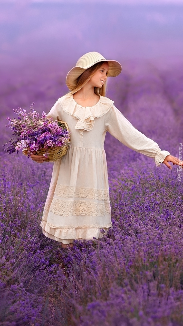 Dziewczynka w kapeluszu z koszykiem kwiatów