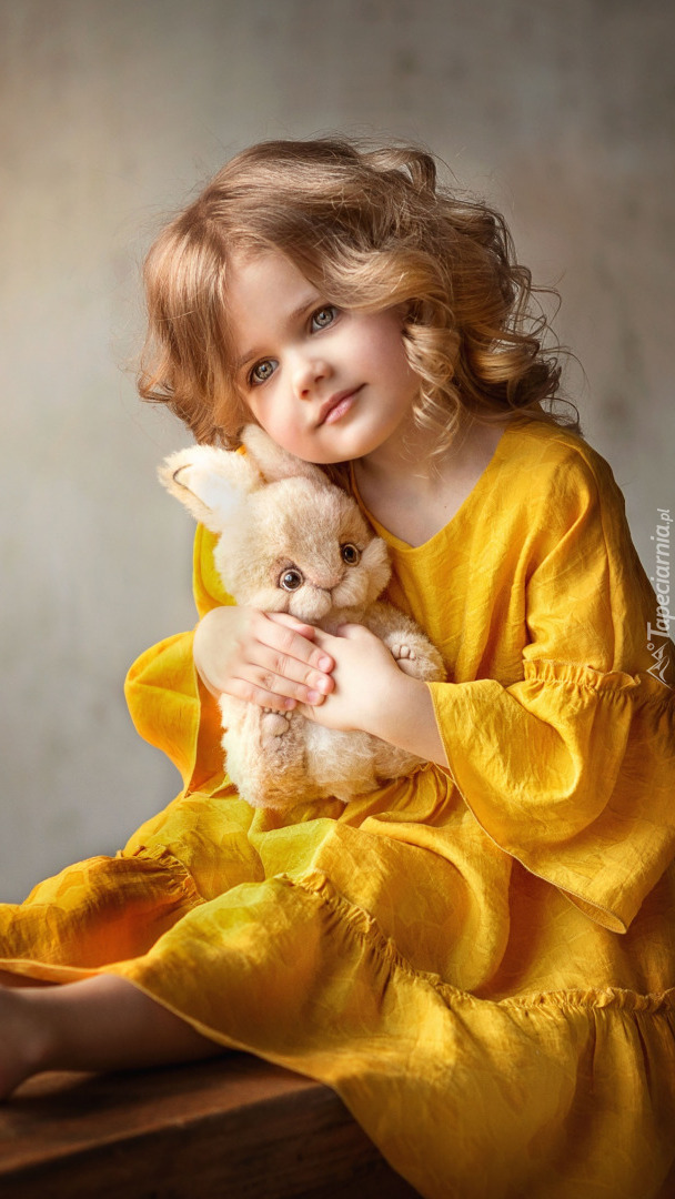Dziewczynka w żółtej sukience z pluszowym króliczkiem