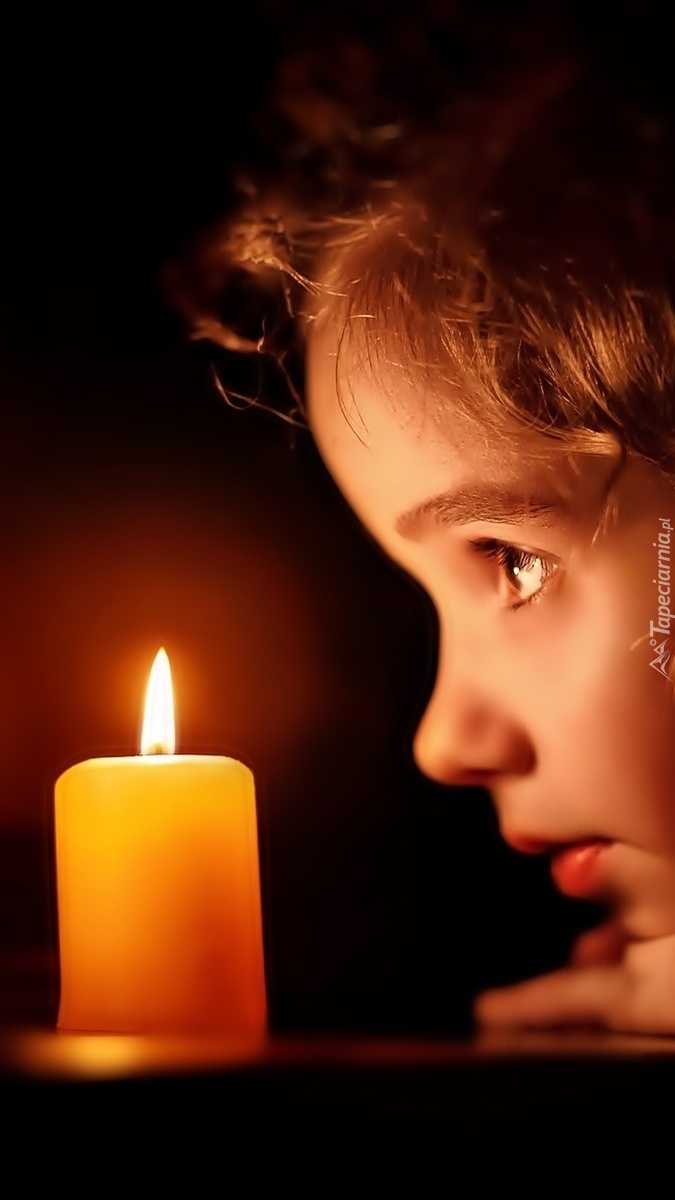 Dziewczynka wpatrujaca się w płomień świecy