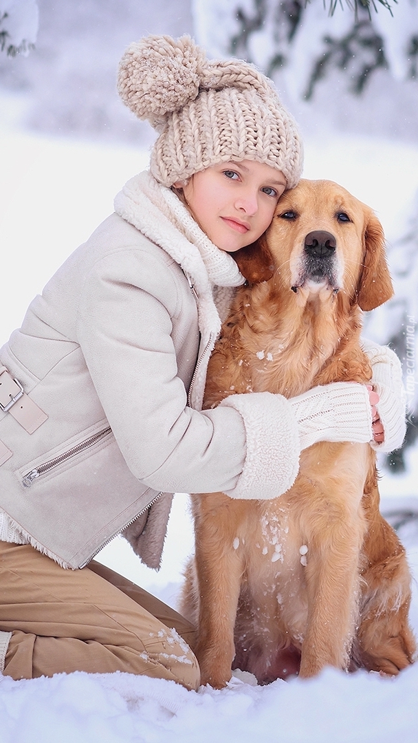 Dziewczynka z golden retrieverem na śniegu