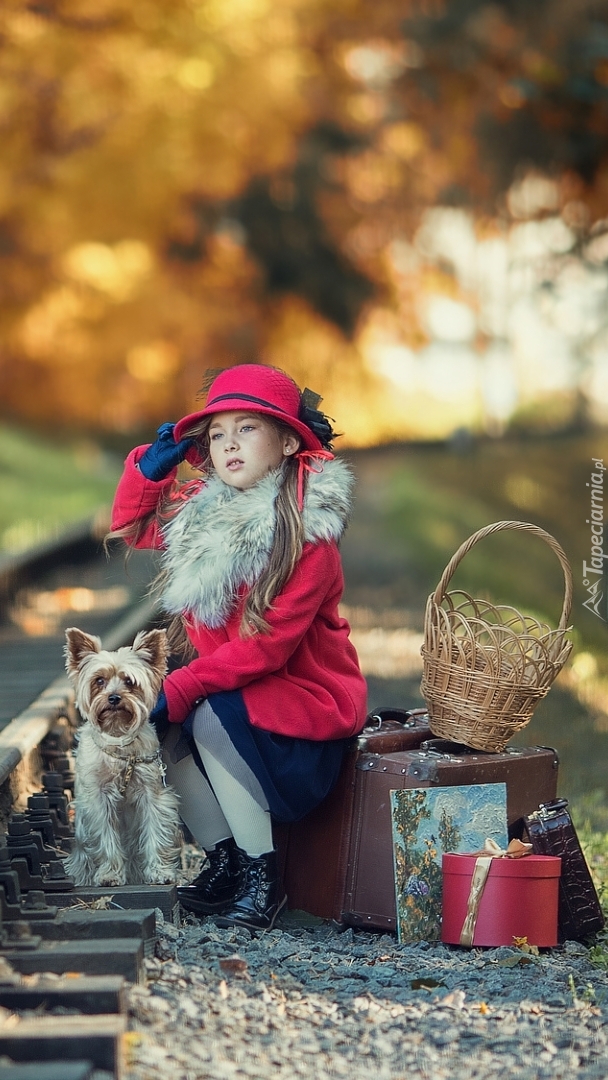 Dziewczynka z psem i bagażami przy torach