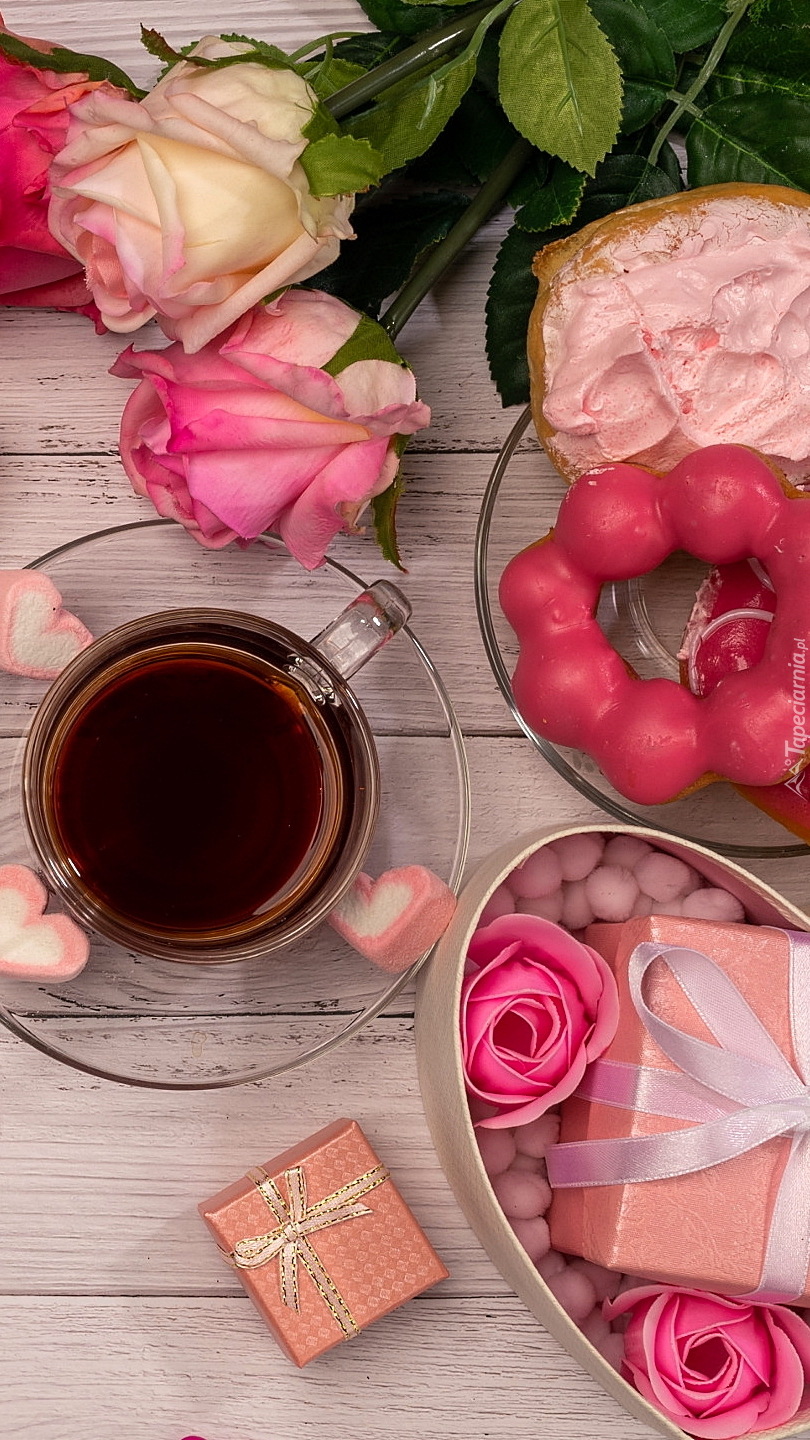 Filiżanka kawy i pączki obok róż