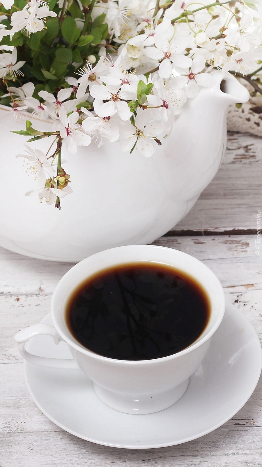 Filiżanka kawy obok wazonu z kwiatami