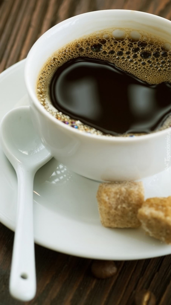 Filiżanka kawy z brązowym cukrem i łyżeczką na spodku