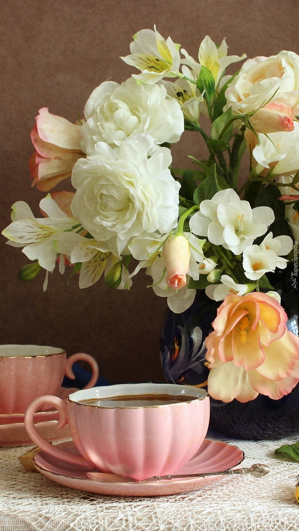 Filiżanki obok wazonu z kwiatami
