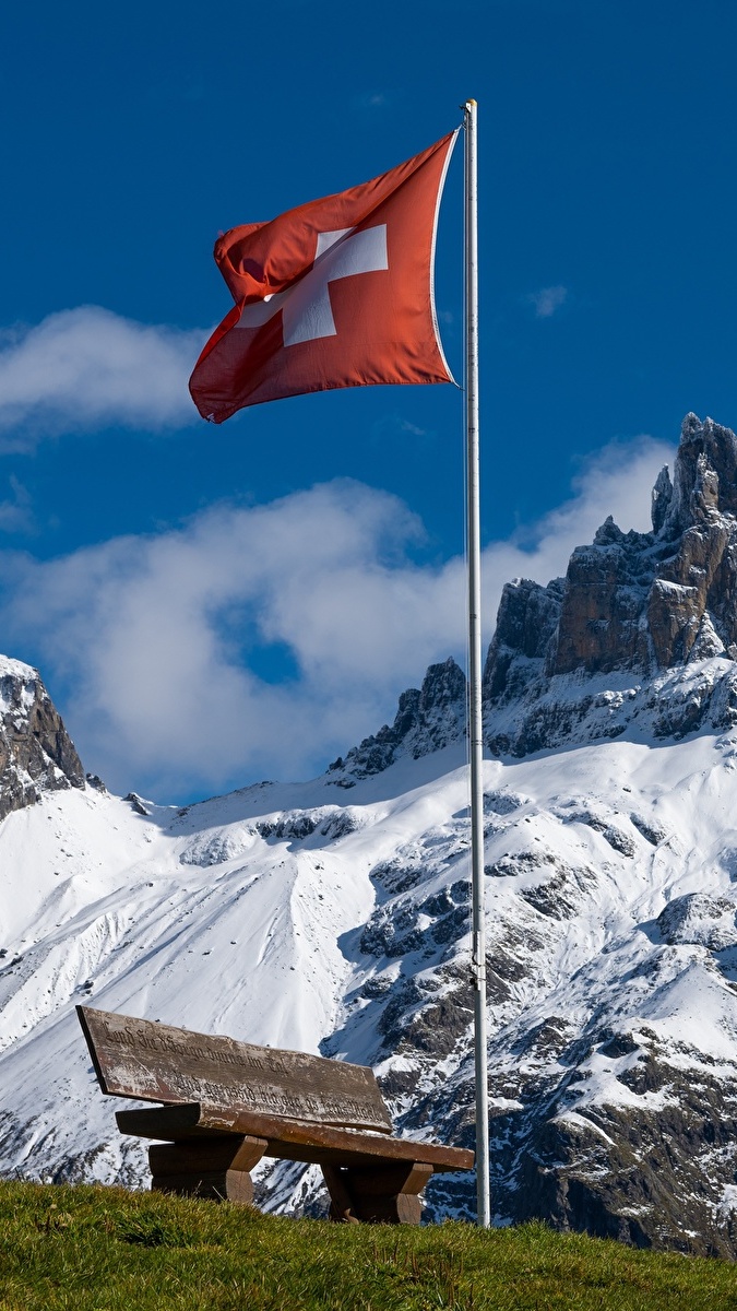 Flaga Szwajcarii obok ławki w ośnieżonych Alpach