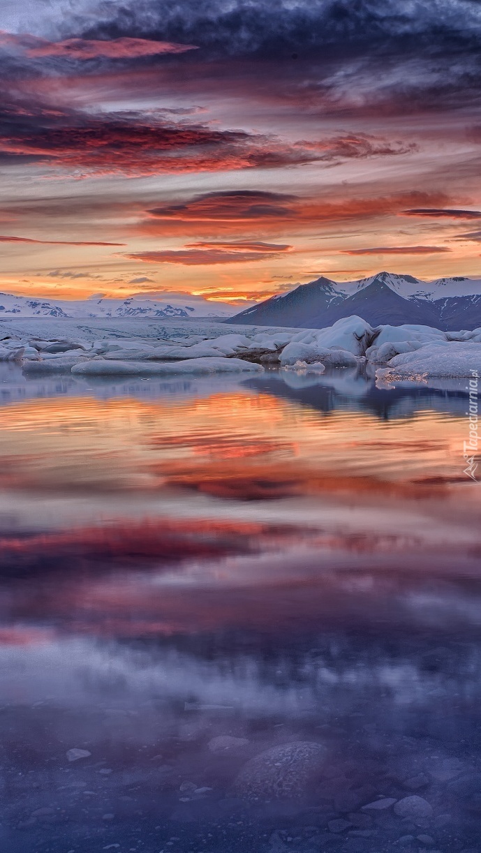 Góry i niebo zimą odbijające się w wodzie o zachodzie słońca