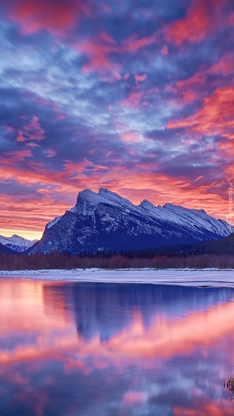 Jezioro i góry w uścisku mroźnej zimy o zachodzie słońca