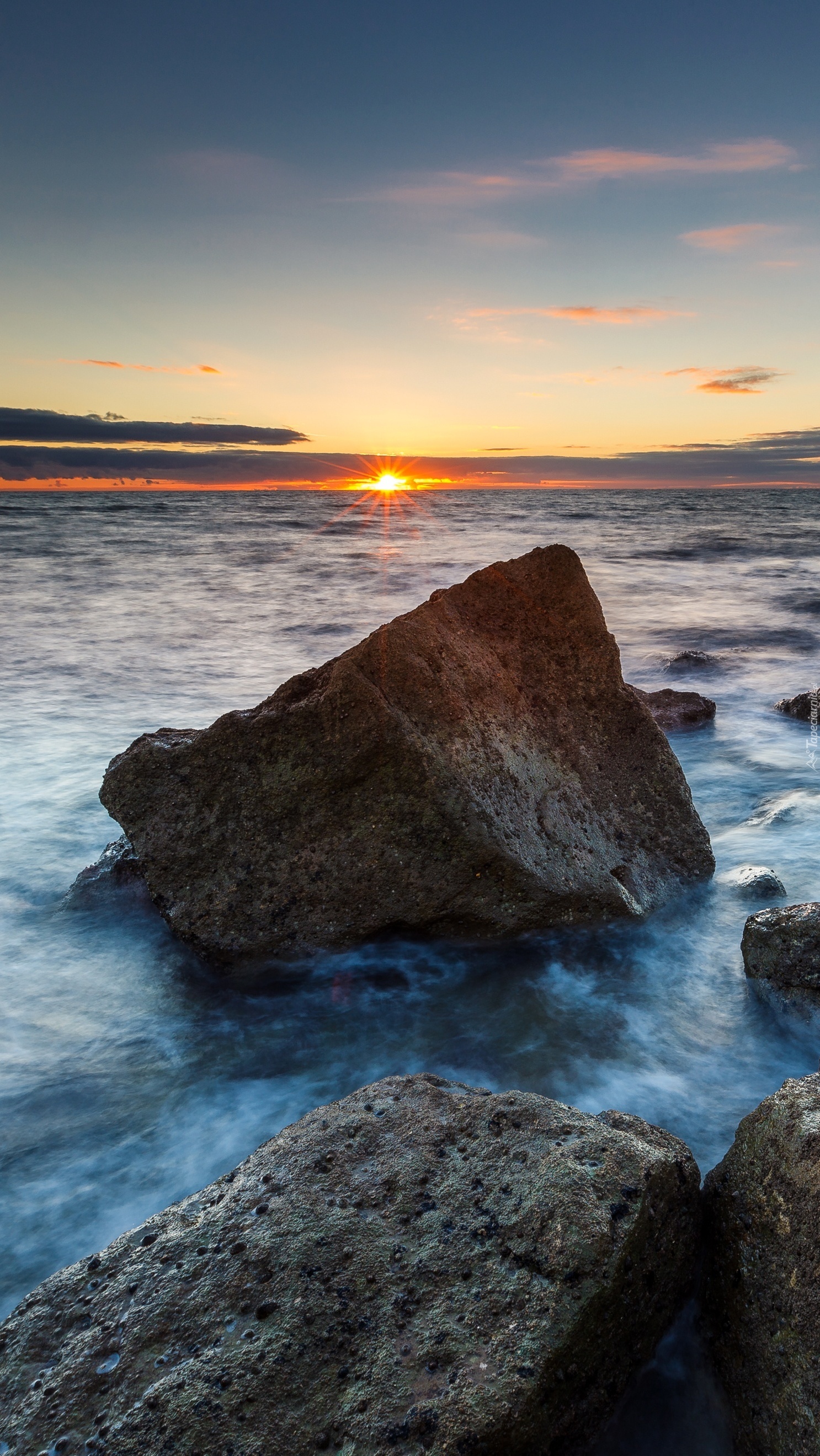 Kamienie na brzegu morza w promieniach zachodzącego słońca