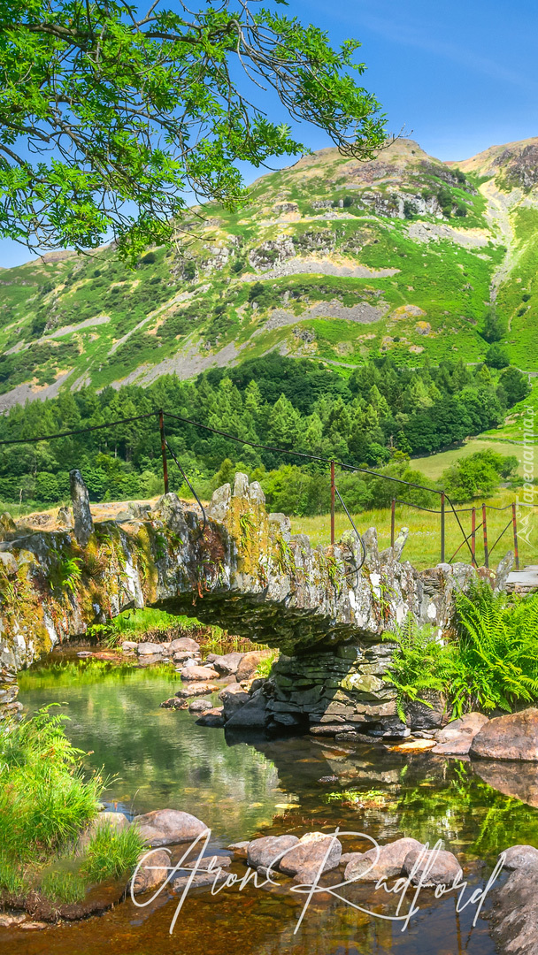 Kamienny mostek na tle zielonego wzgórza