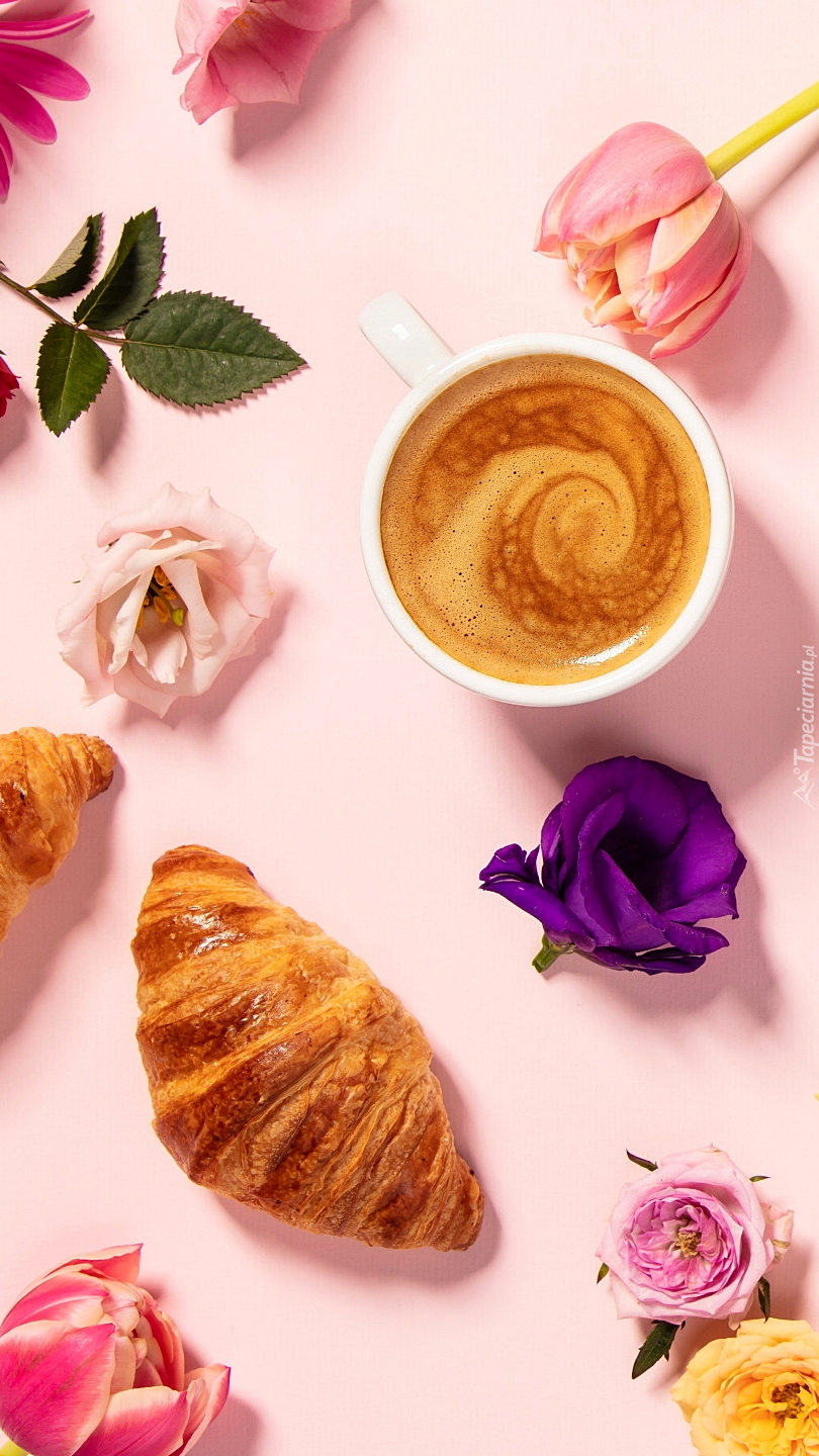 Kawa i croissant pośród kwiatów