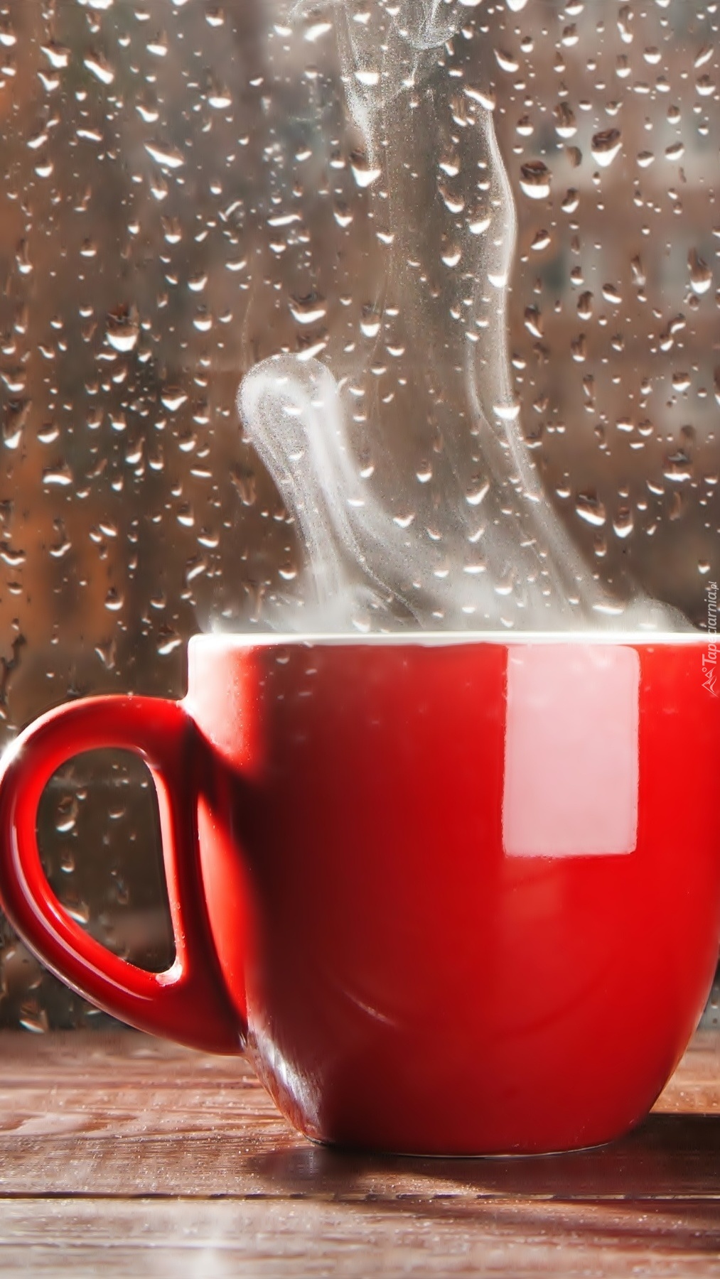 Kawa w czerwonej filiżance przy szybie w kroplach deszczu