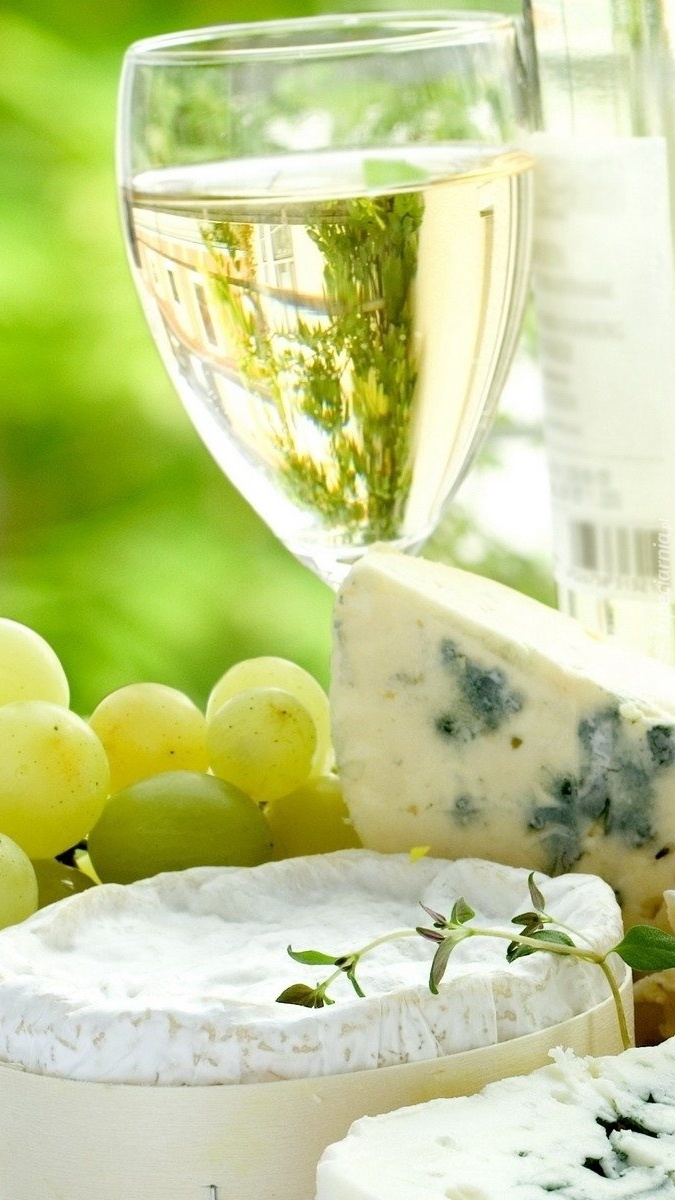 Kieliszek białego wina obok serów